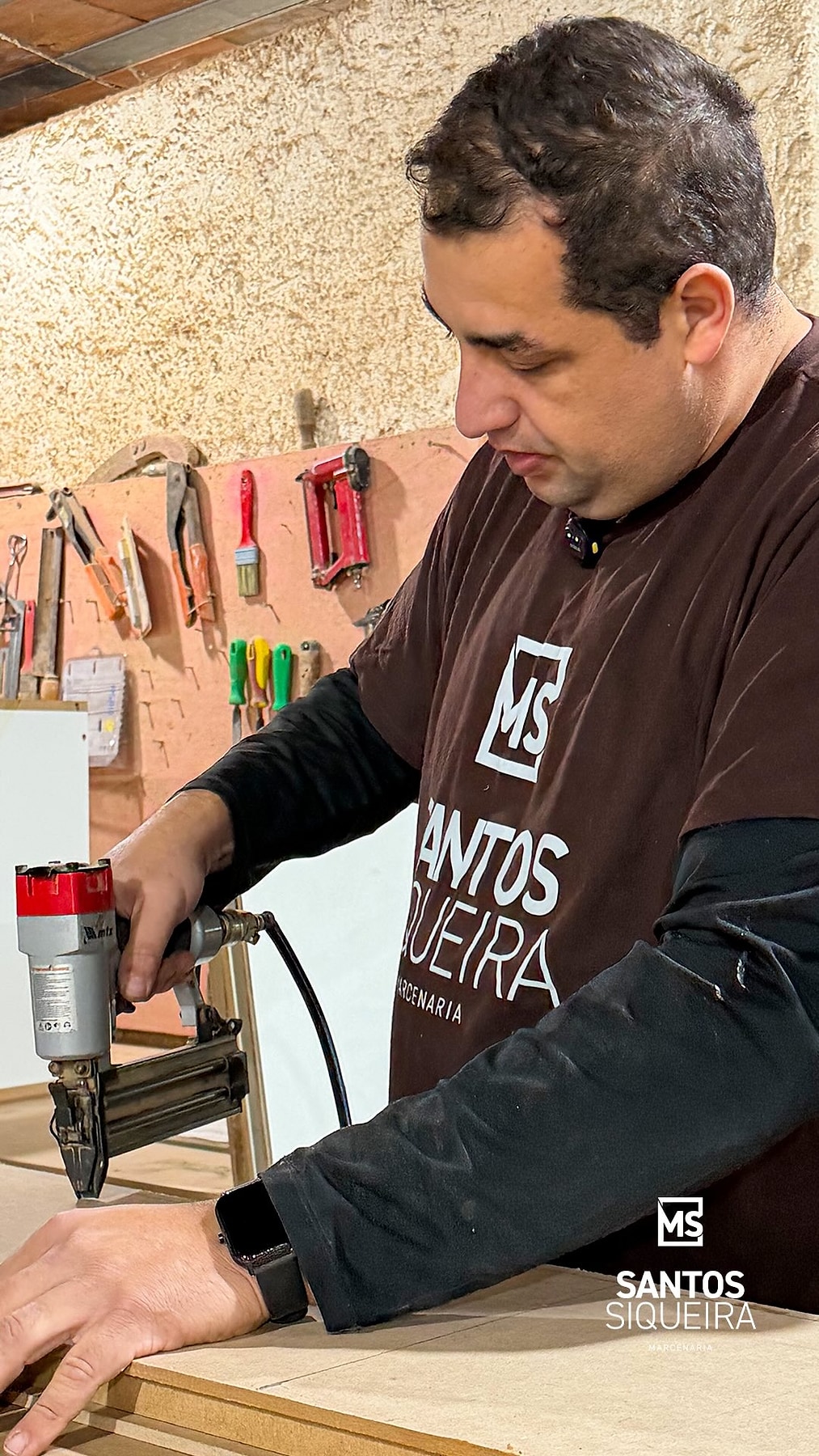 Marceneiro da Santos Siqueira montando a estrutura de um móvel na oficina com pinadora pneumática