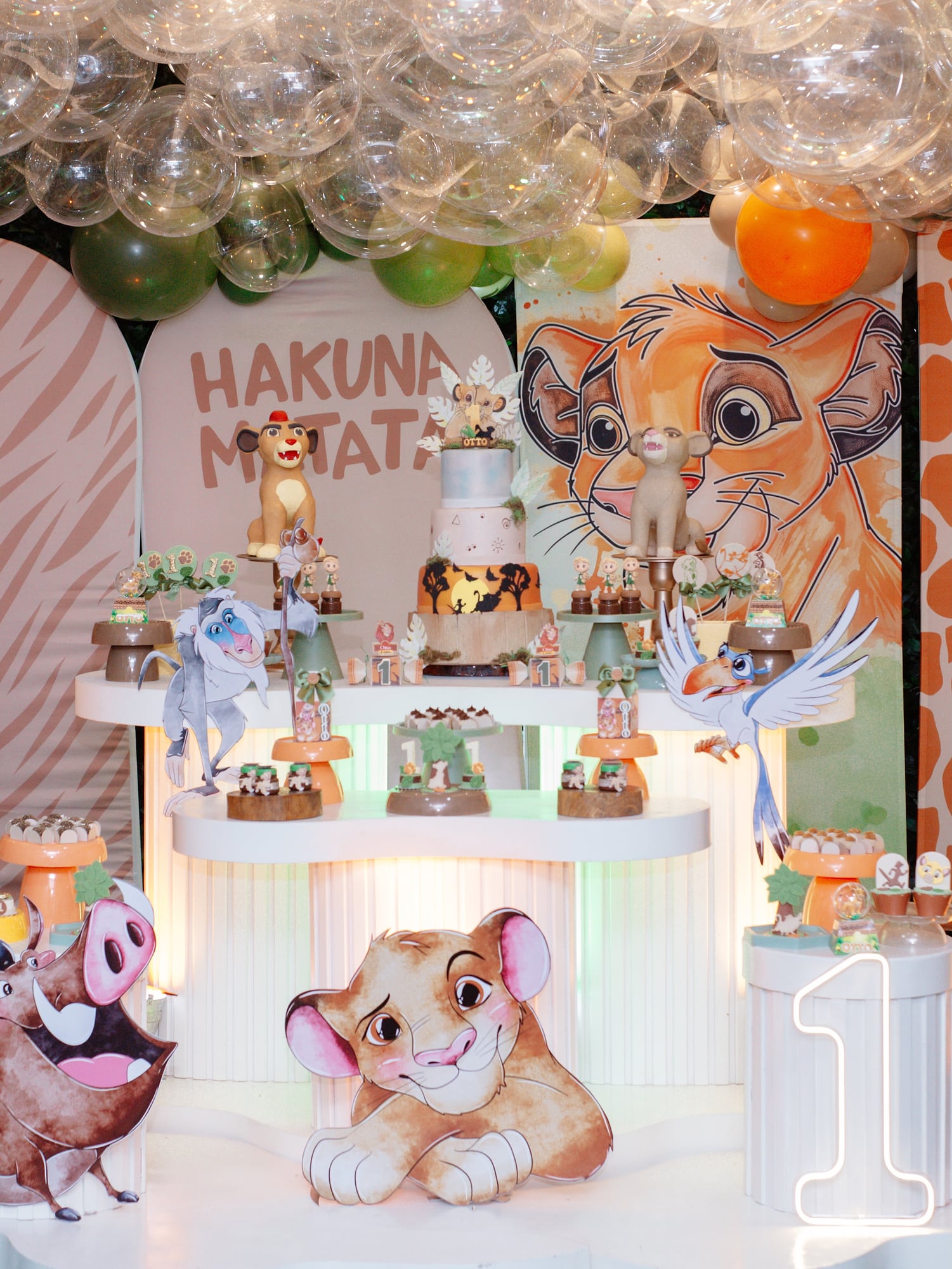 Mesa de doces do Rei Leão com o painel Hakuna Matata e bolhas no teto